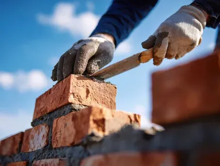Brick being set on mortar with a trowel